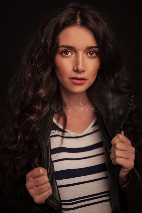 Young woman pulling on her lather jacket`s collars