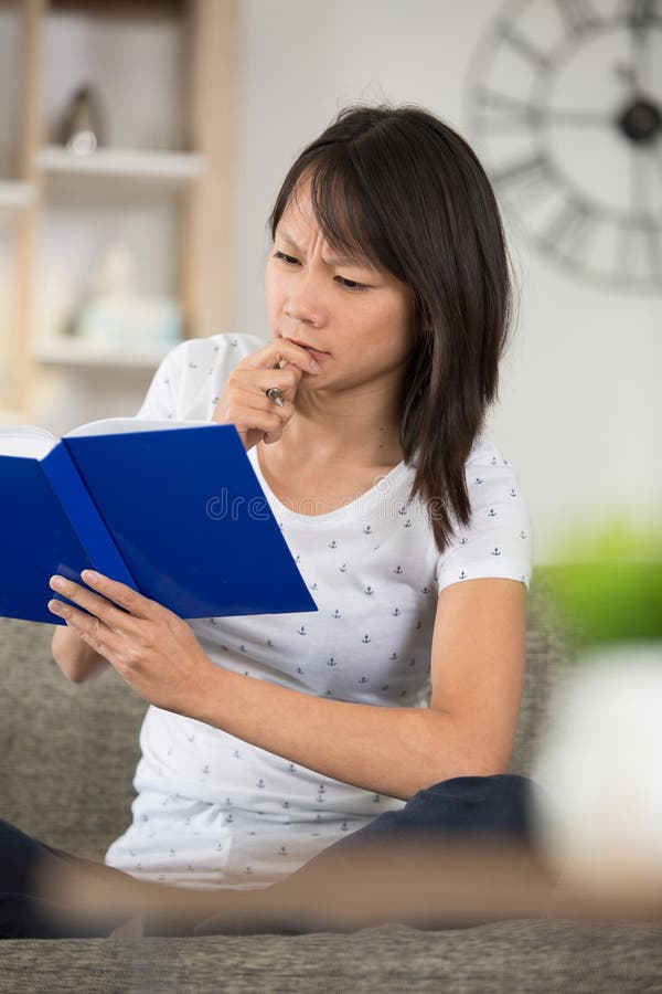 Young woman reading book and frowning royalty free stock image