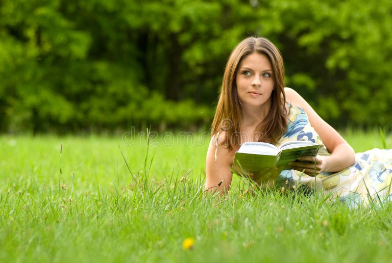 Giovane donna, libro di lettura in parco.