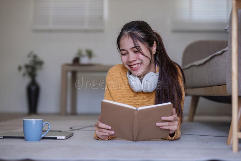 Young woman reading book on sofa in living room.