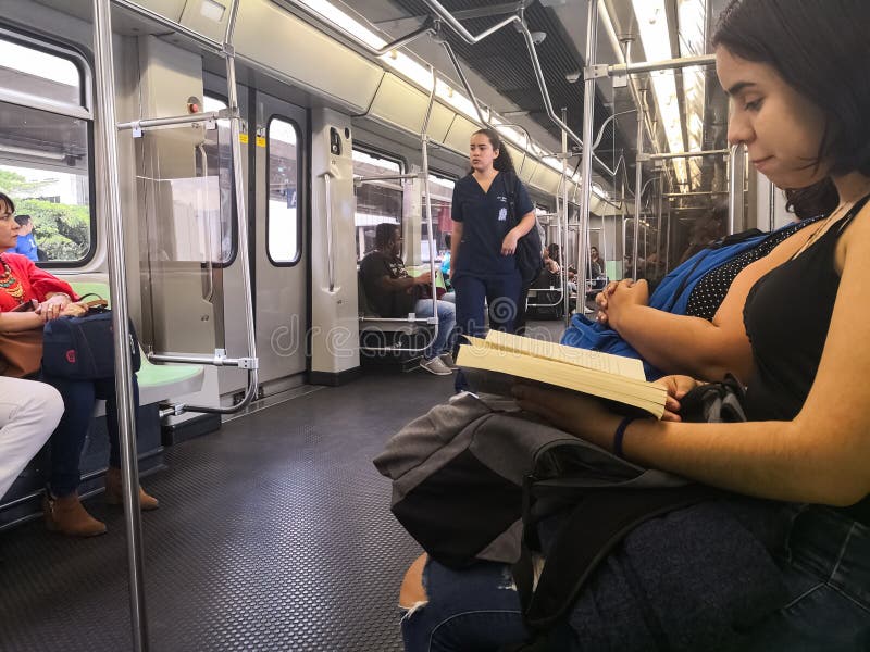 Young woman reading a book while traveling inside the Metro of Medellin stock photo Young woman reading a book while traveling inside the Metro of Medellin stock photo