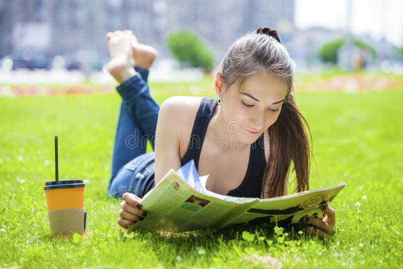 Young woman reading magazine lying on grass