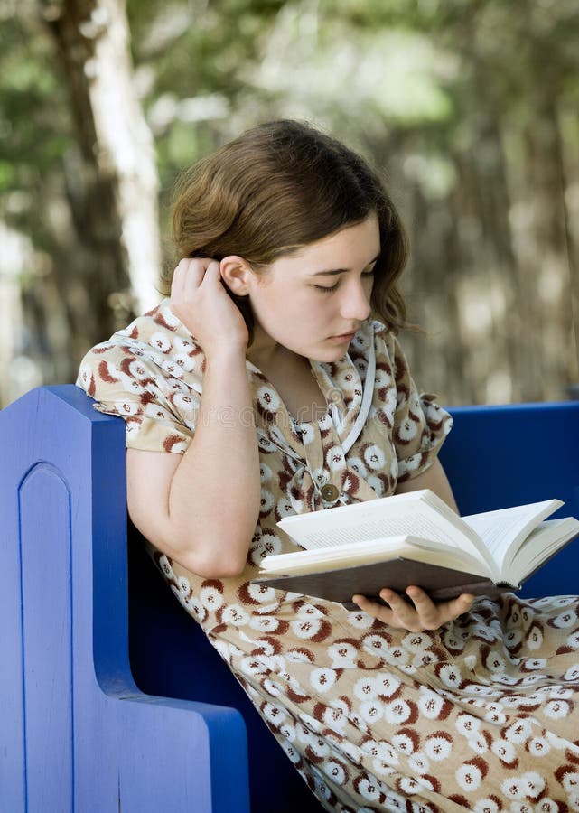 Pretty young woman/girl reading a book outdoors; soft focus portrait. Pretty young woman/girl reading a book outdoors; soft focus portrait