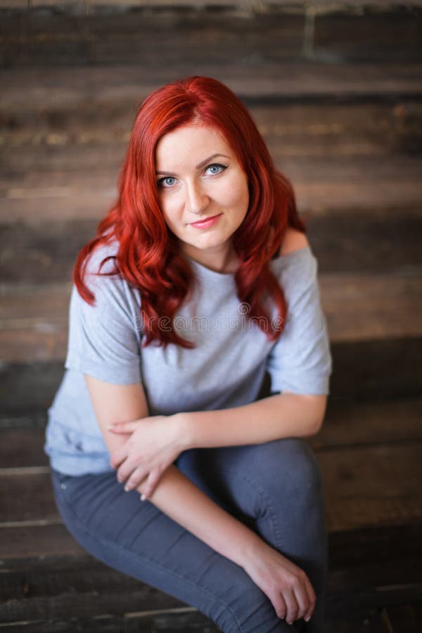 Young woman with red long hair indoor portrait on wooden background royalty free stock photography Young woman with red long hair indoor portrait on wooden background royalty free stock photography