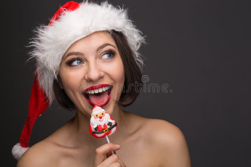 young woman in a red skirt and santa claus hat on a light background celebrates christmas