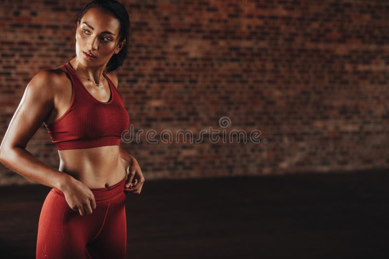 Young woman posing in fitness outfit. Portrait of young sports woman  relaxing outdoors after workout. Female jogger in bright sportswear smiling  looking away, advertising for sports Stock Photo