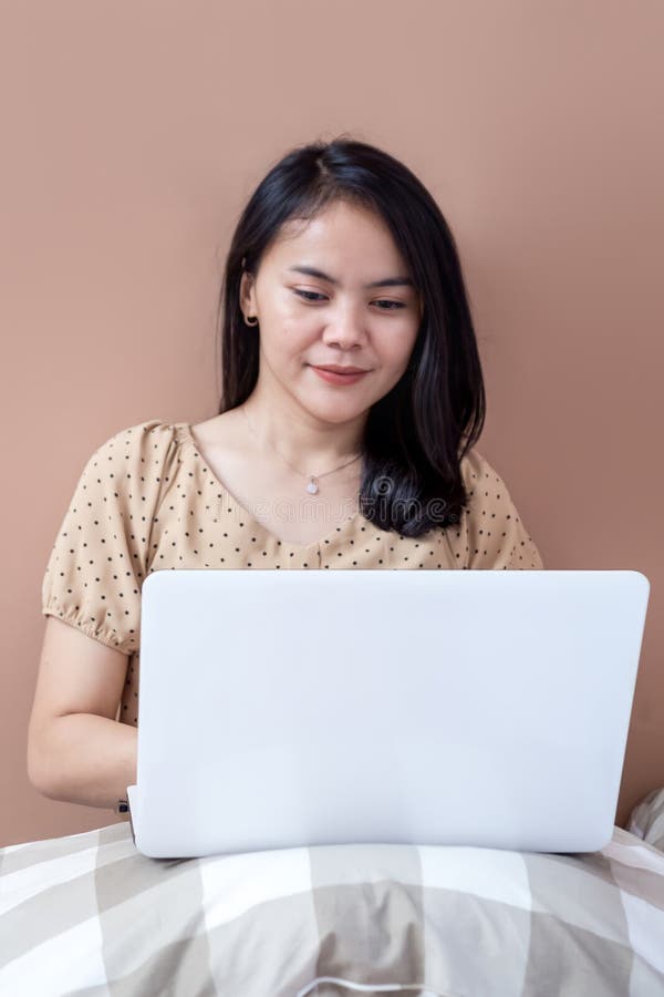 Young Woman Relaxing in Bed Looking at Laptop Screen Stock Image