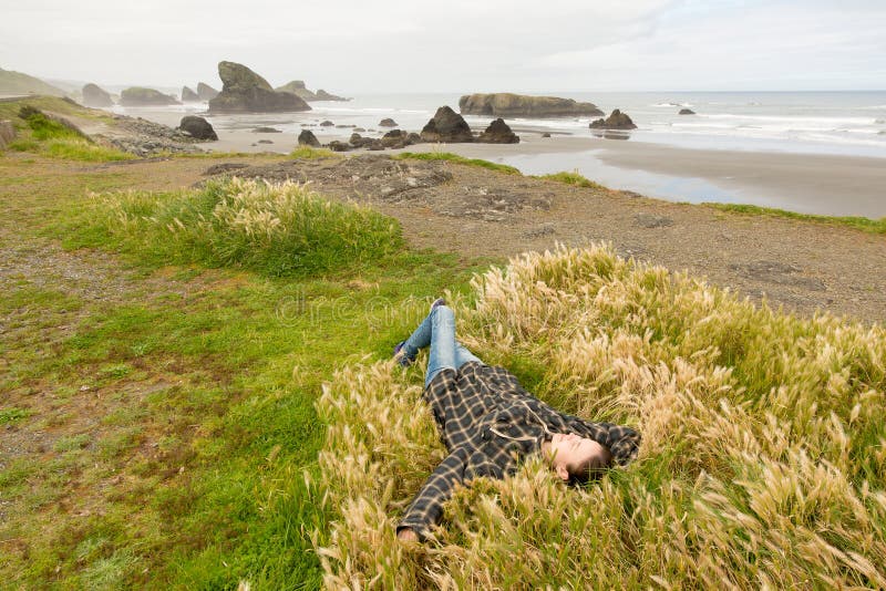 Young woman relaxing on rock near Pacific ocean.