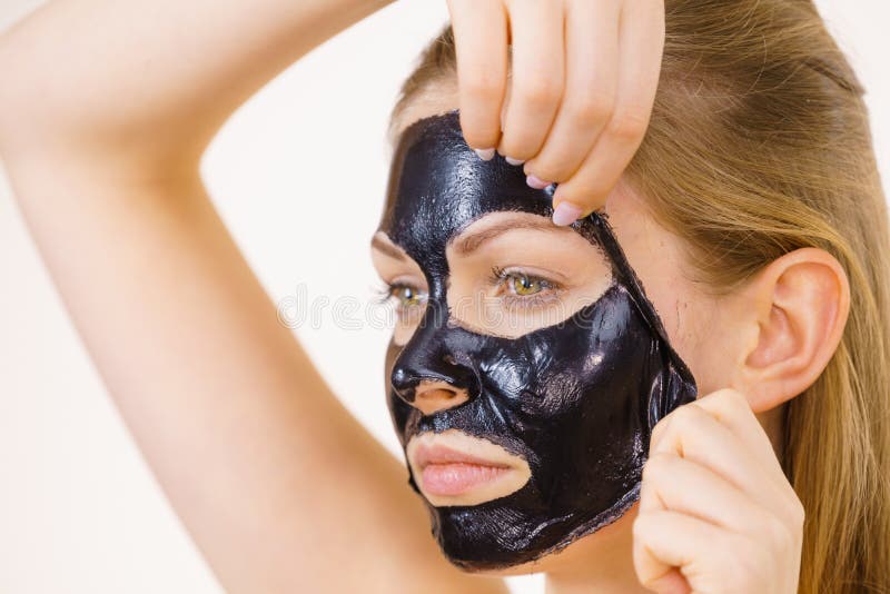 Girl removes black mask from face stock photo Girl removes black mask from face stock photo