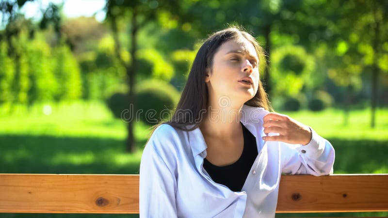 Young woman resting on bench in park suffering from heat and stuffiness, pms royalty free stock photos Young woman resting on bench in park suffering from heat and stuffiness, pms royalty free stock photos
