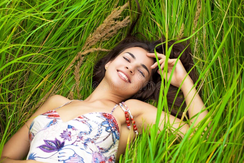 Young woman resting and day lying down on green grass