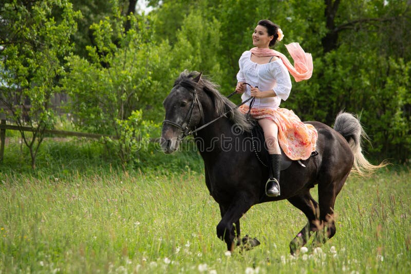 Young woman riding on beautiful horse , having fun in summer time , Romania countryside