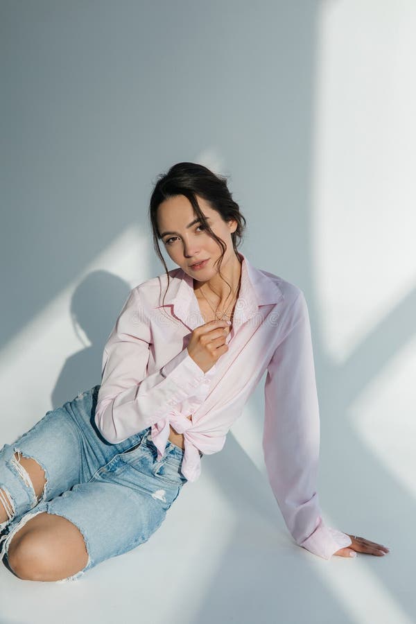 Young Woman in Ripped Jeans and Shirt Sits Sunlit Stock Image - Image ...