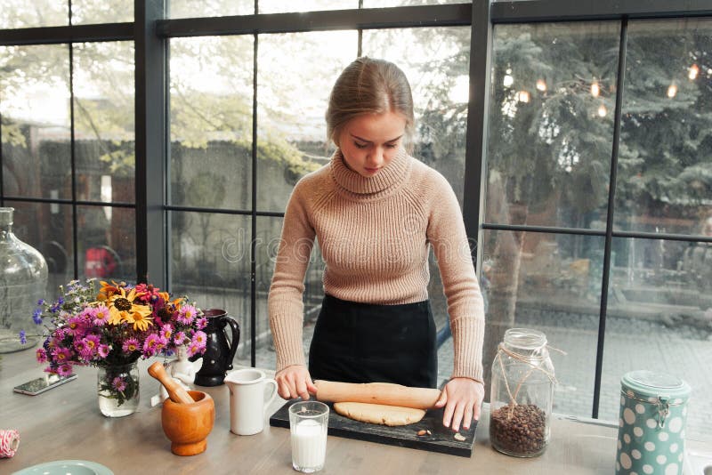 Young woman roll out dough in kitchen. Attractive housewife preparing pie or cookies. Culinary classes, pastry cooking, homemade cuisine concept