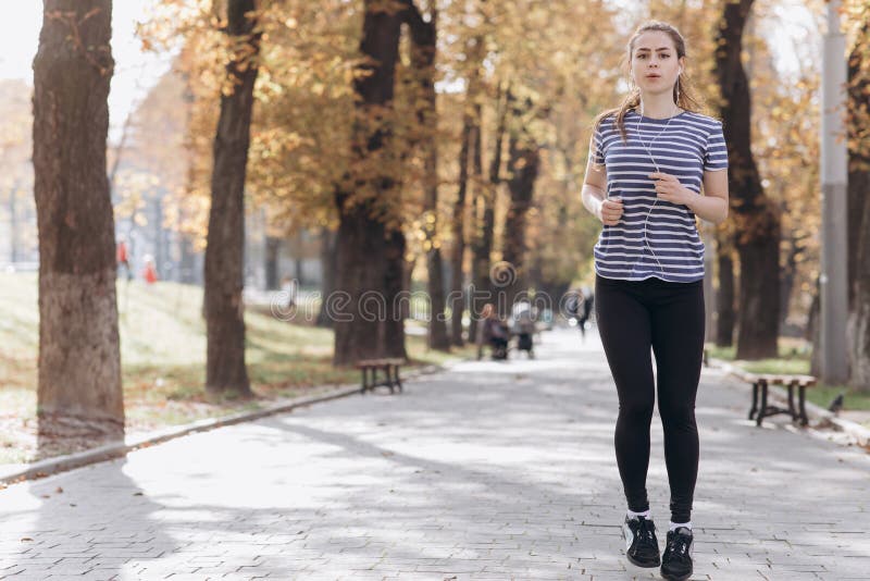 Young woman runner training in summer park. Close up fitness woman jogging outdoor. Tired girl jogger breathing after