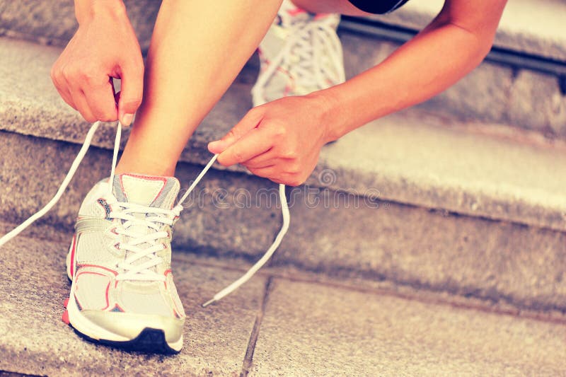 Young woman runner tying shoelace