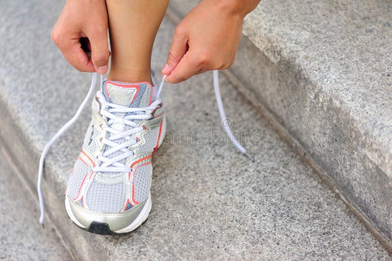 Young woman runner tying shoelace