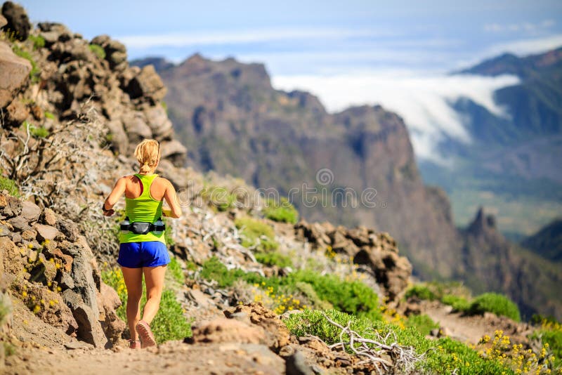 Young woman running or power hiking in mountains on sunny summer day. Beauty female runner jogging and exercising outdoors in nature, rocky trail footpath on La Palma, Canary Islands. Young woman running or power hiking in mountains on sunny summer day. Beauty female runner jogging and exercising outdoors in nature, rocky trail footpath on La Palma, Canary Islands