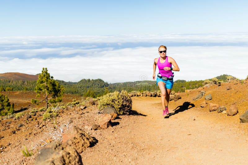 Young woman running in mountains on sunny summer day. Beauty female runner jogging and exercising outdoors in nature, rocky trail footpath on La Palma, Canary Islands