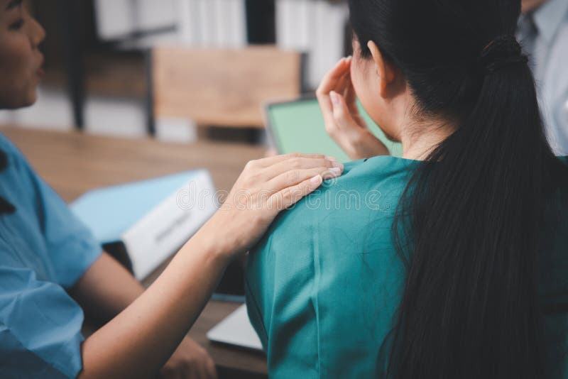 A young woman `s hand resting on her friend`s shoulder to comfort and encourage her