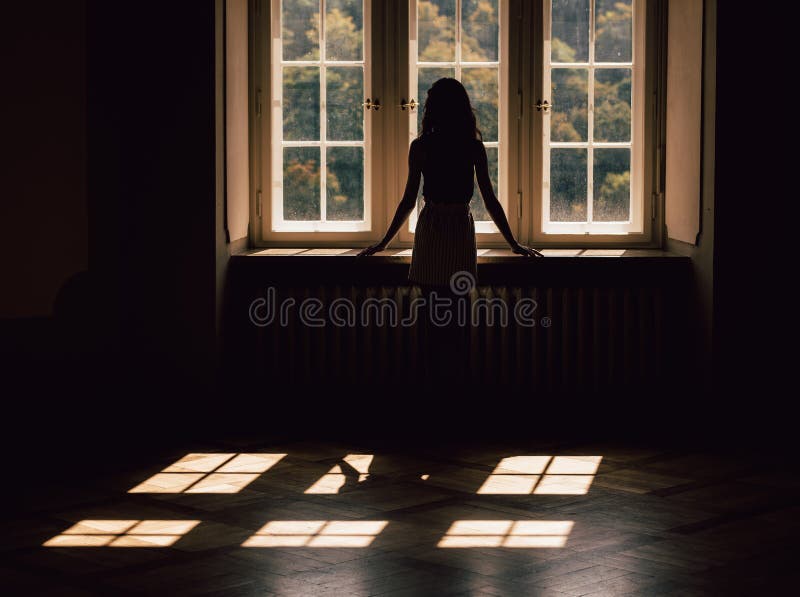 Young woman silhouette, looking through the window stock photo Young woman silhouette, looking through the window stock photo