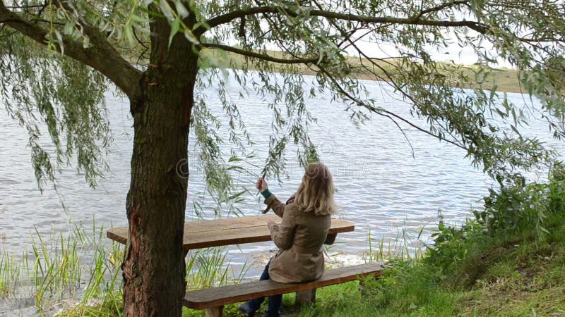 Young woman sit bench ripple lake water play willow tree branch