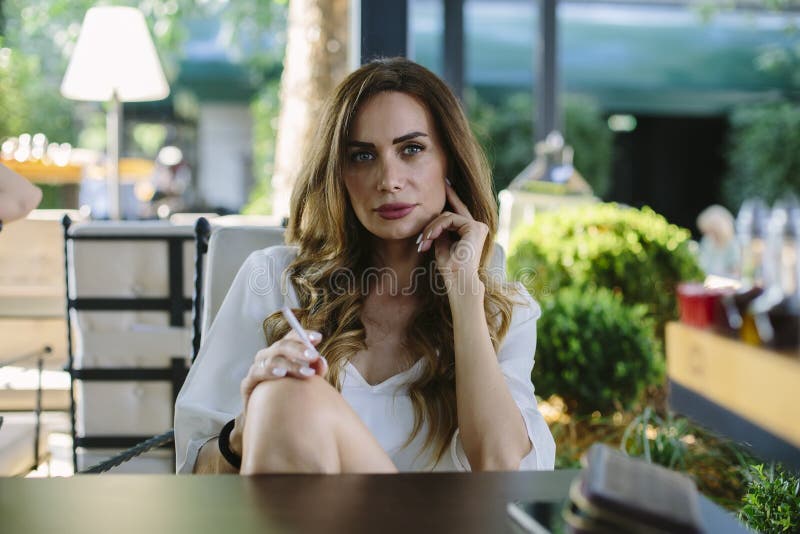 Young woman smokes a cigar at a restaurant stock photo Young woman smokes a cigar at a restaurant stock photo