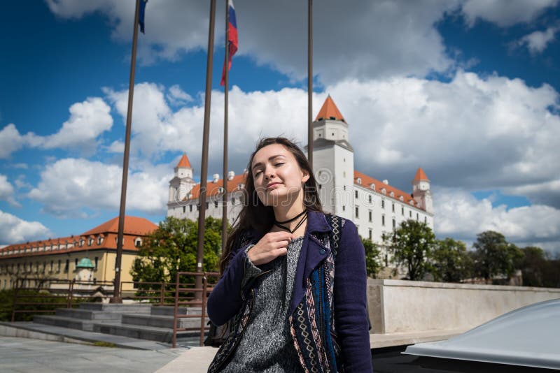 Young woman sits on square with a view on castle