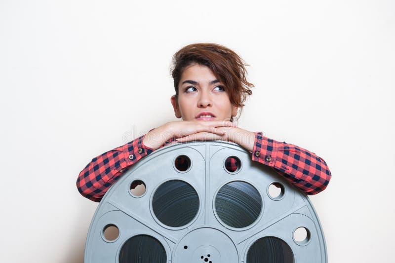 Young woman sitting behind big cinema movie reel stock images Young woman sitting behind big cinema movie reel stock images