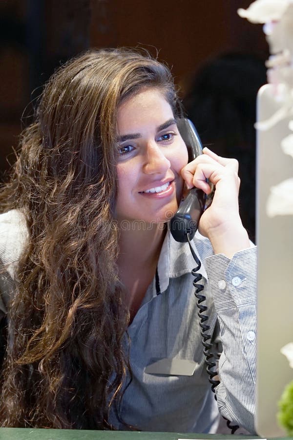 Young woman sitting at her desk working and answering a phone ca royalty free stock image Young woman sitting at her desk working and answering a phone ca royalty free stock image