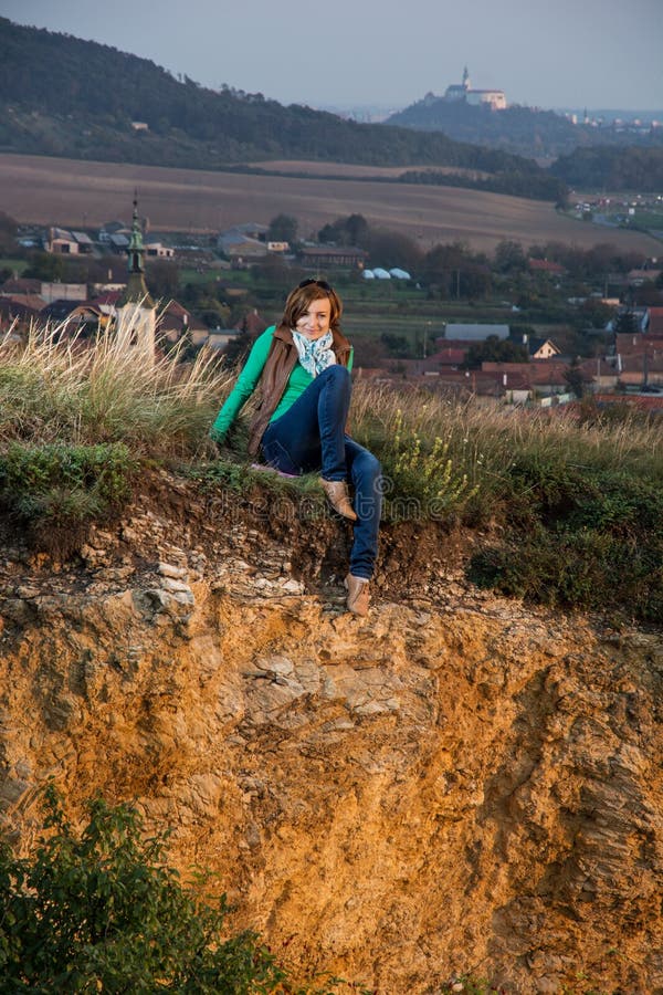 Mladá žena sedí na vápencovej skale pri západe slnka