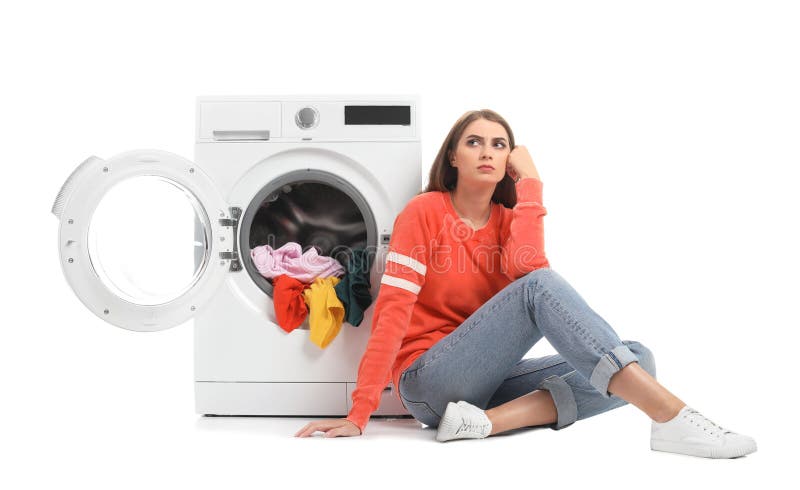 Young woman sitting near washing machine with dirty laundry. 