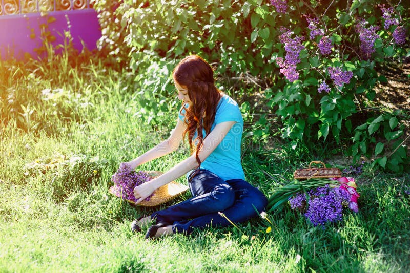 Young woman sitting in the park on the grass with flowers stock photography Young woman sitting in the park on the grass with flowers stock photography