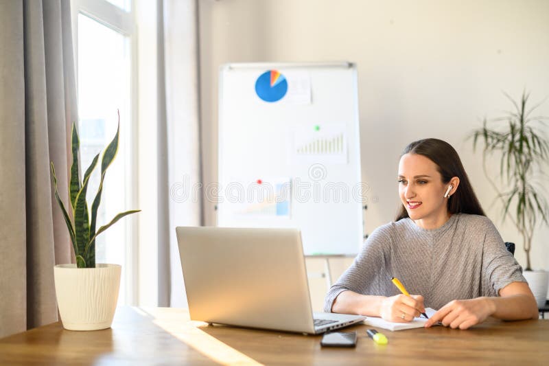 A young woman sits at a table with a laptop