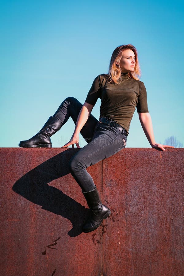 Young Woman Sitting on a Wall Looking Towards the Sun Stock Photo ...