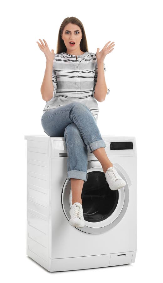 Young woman sitting on washing machine against white background. 