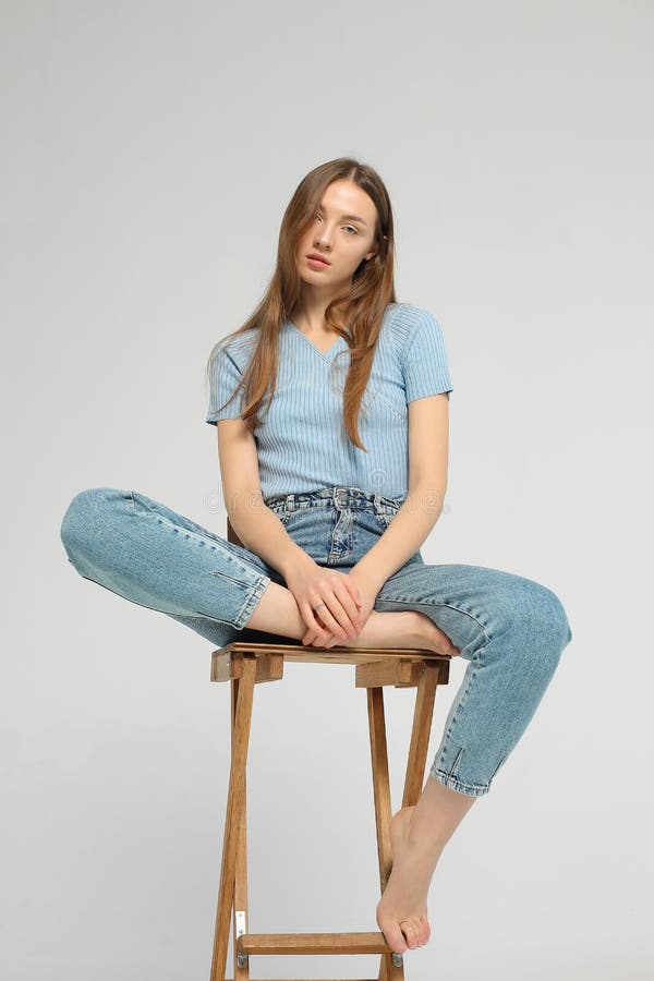 Young woman is sitting on wooden chair in studio royalty free stock photography Young woman is sitting on wooden chair in studio royalty free stock photography