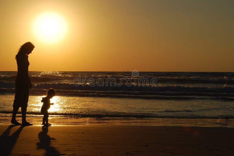 Giovane donna con un bambino piccolo sul mare e sul tramonto.