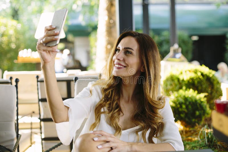 Young woman with smart phone sitting in restaurant stock photo Young woman with smart phone sitting in restaurant stock photo