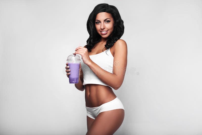 Young woman in sports gym wear with fruit fresh drink