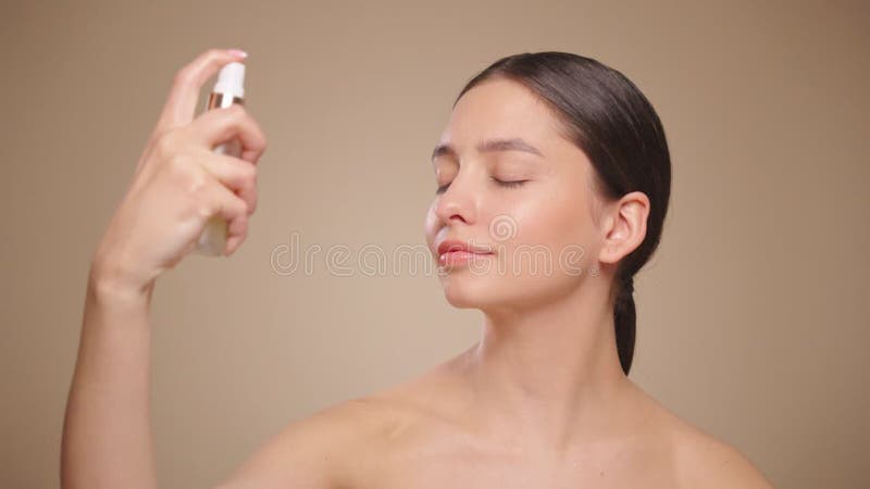 Young woman sprays a facial spray mist or thermal wate
