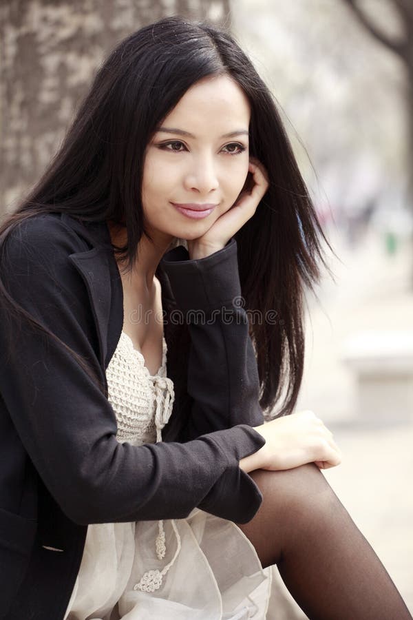 Young Asian woman with long hair sitting and enjoying the scenery in spring. Young Asian woman with long hair sitting and enjoying the scenery in spring.