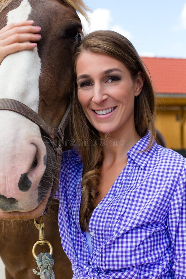 Young woman in the stable with horse in sunshine