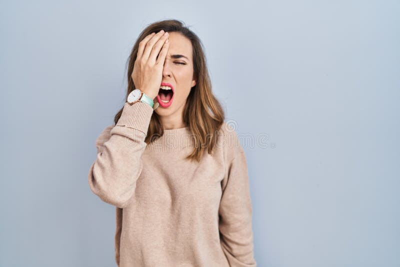 Young woman standing over isolated background yawning tired covering half face, eye and mouth with hand