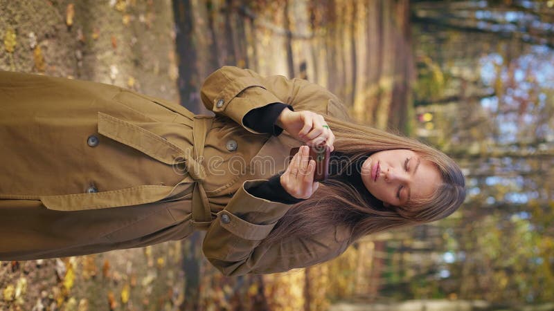 Tânără care stă în parc folosind smartphone-uri cu dureri de cap. stock footage