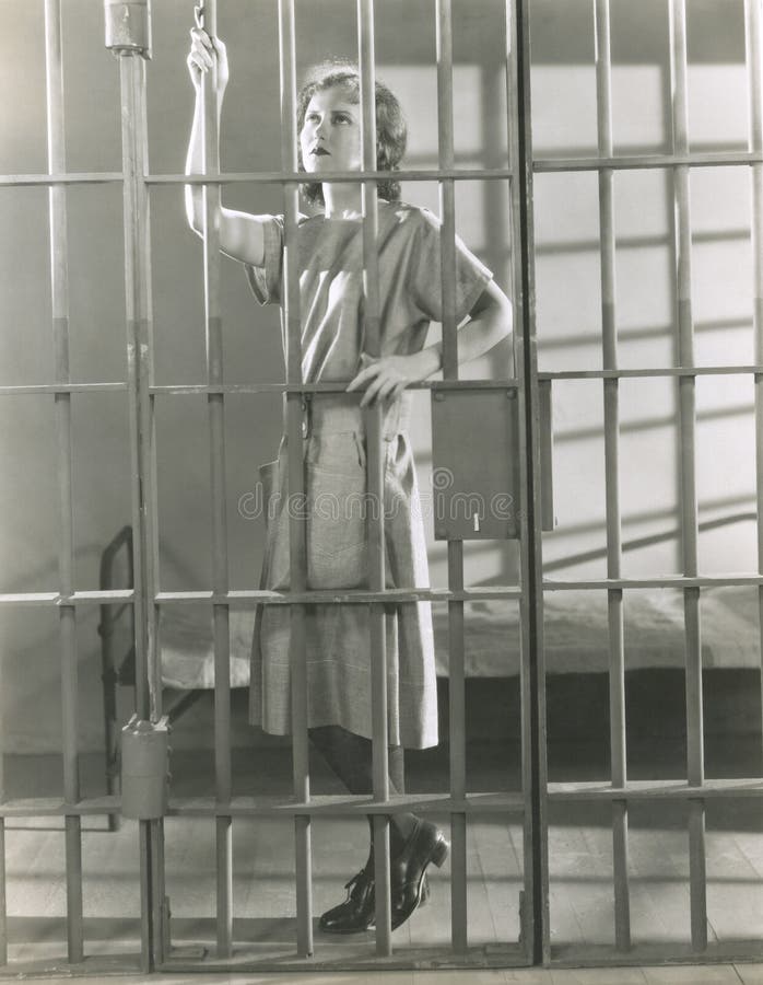Young woman standing in prison cell stock photo Young woman standing in prison cell stock photo