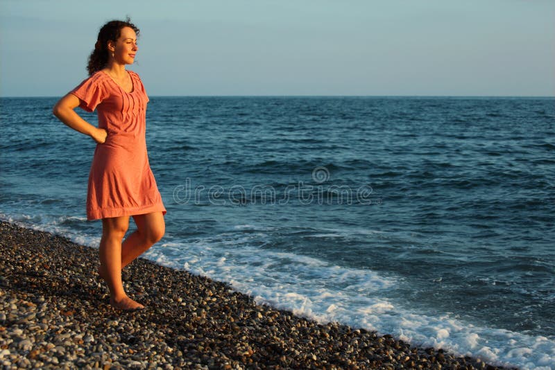 Young woman stands ashore of sea