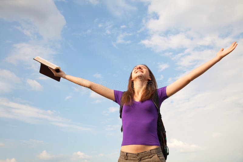 Young woman staying with raised hands against blue sky