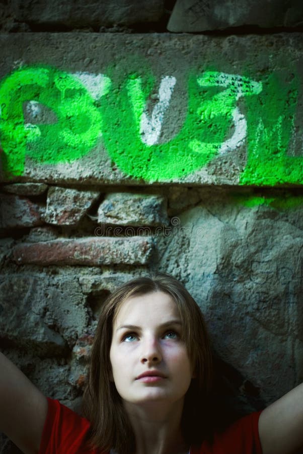 Retrato lindo mujer joven de pie antes piedra muro elevado espalda, buscando arriba.