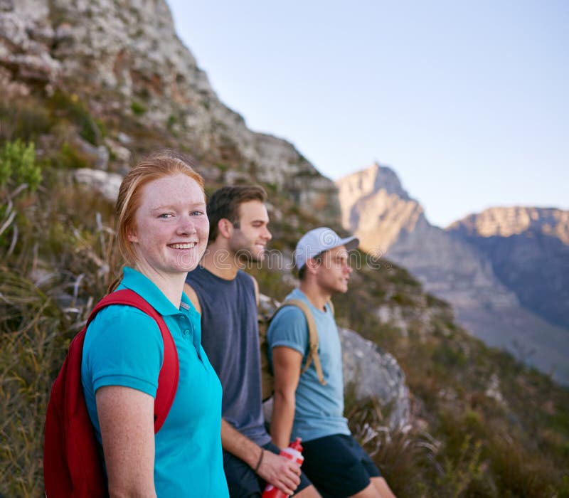 Pretty female student resting with friends while hiking on a nature trail. Pretty female student resting with friends while hiking on a nature trail